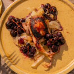 roasted chick witih grapes on a yellow dish